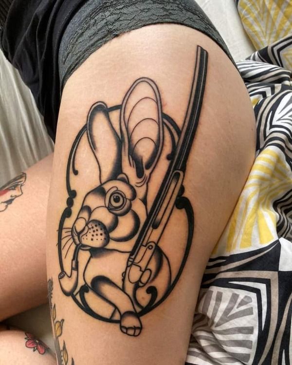 Xăm hình con thỏ ở chân ôm cây súng ngắn